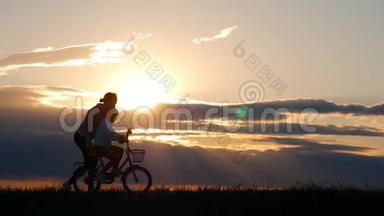 <strong>剪影</strong>自行车可爱的家庭在草地上日落时间。母亲和<strong>婴儿</strong>在日落时骑自行车的<strong>剪影</strong>。生活方式